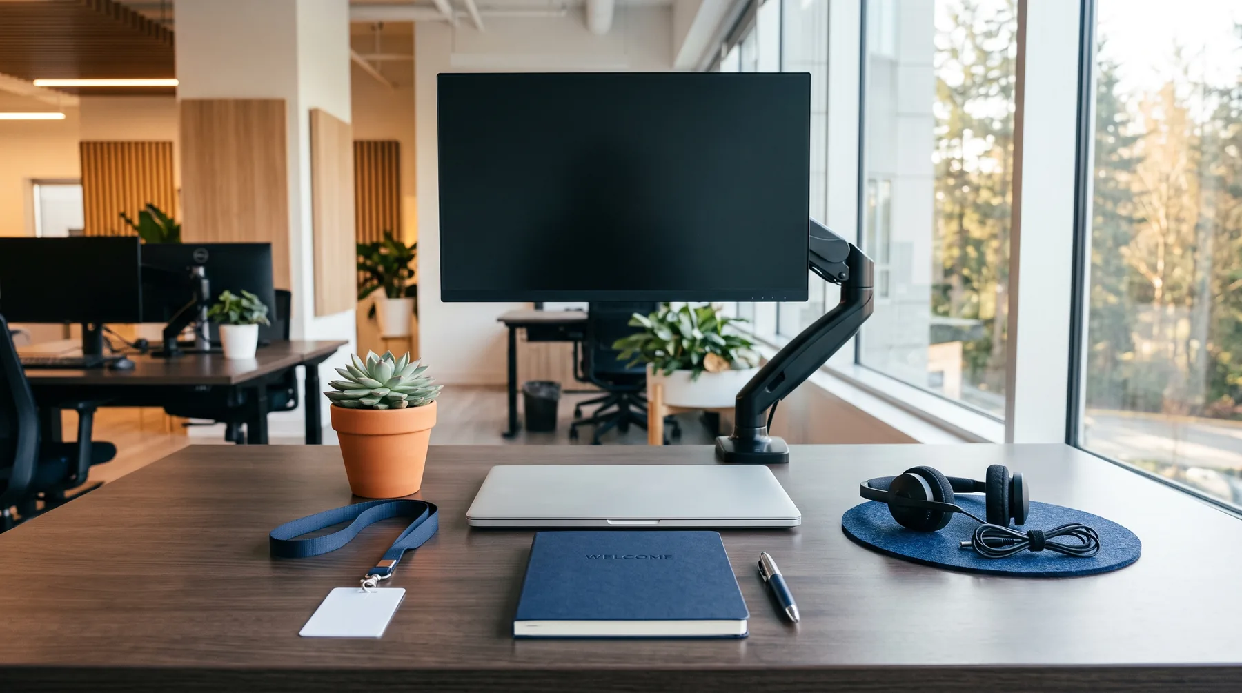 Freshly prepared new-employee desk with a closed laptop, an access card on a lanyard, a headset and a notebook